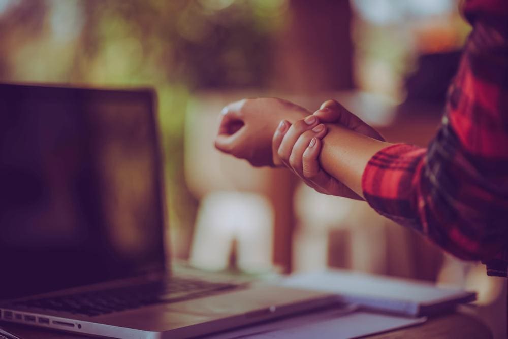 A woman is holding her wrist because she is suffering from carpal tunnel pain.