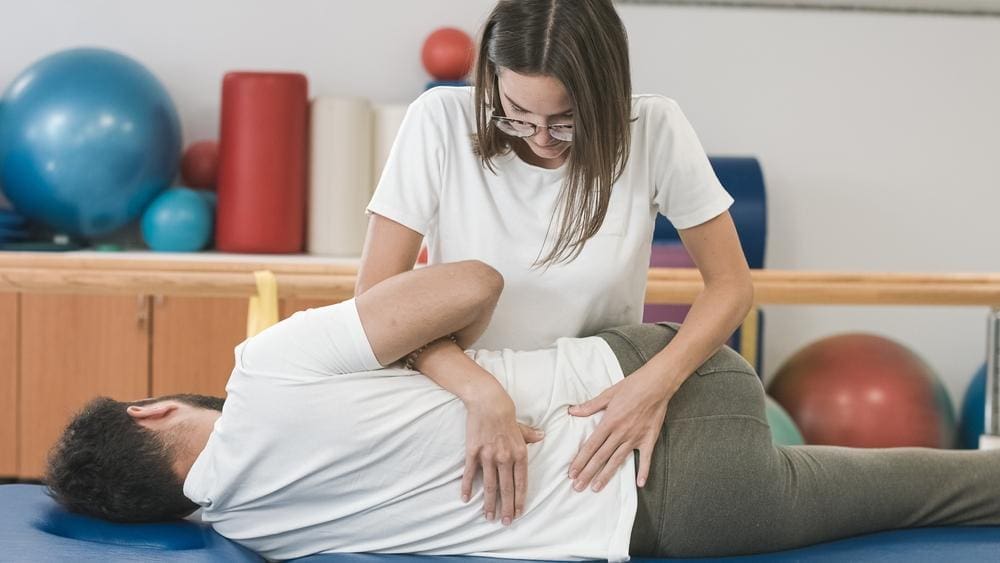 A chiropractor is treating a man for sciatica. 