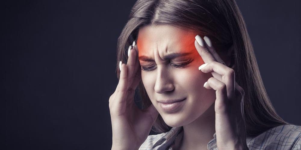 A woman is wincing and rubbing her temples because she has a crippling headache.