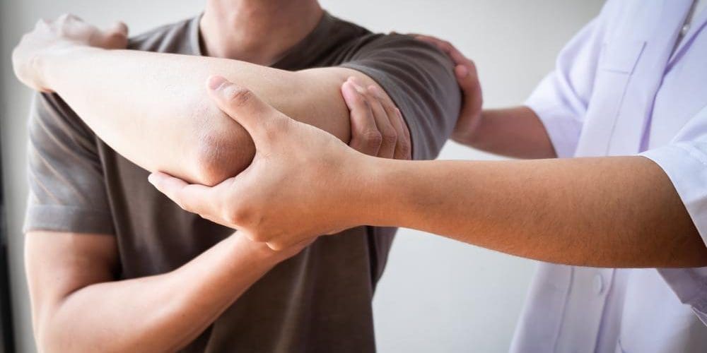 A chiropractor is examining a man's rotator cuff injury.
