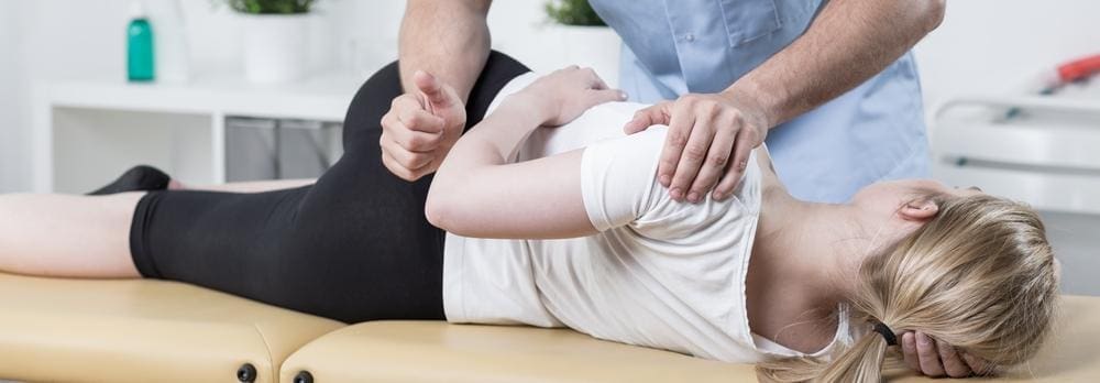 A chiropractor is administering a chiropractic back adjustment for a woman with herniated disc pain.
