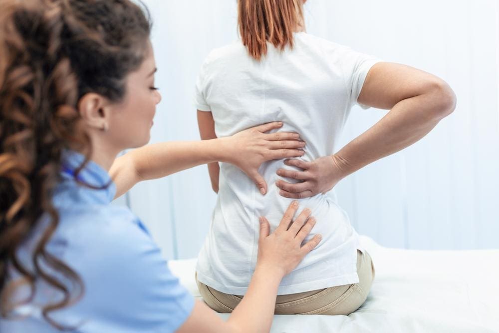 A chiropractor is treating a woman with scoliosis after surgery. 