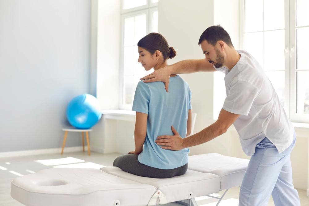 A chiropractor is treating a woman for scoliosis. 