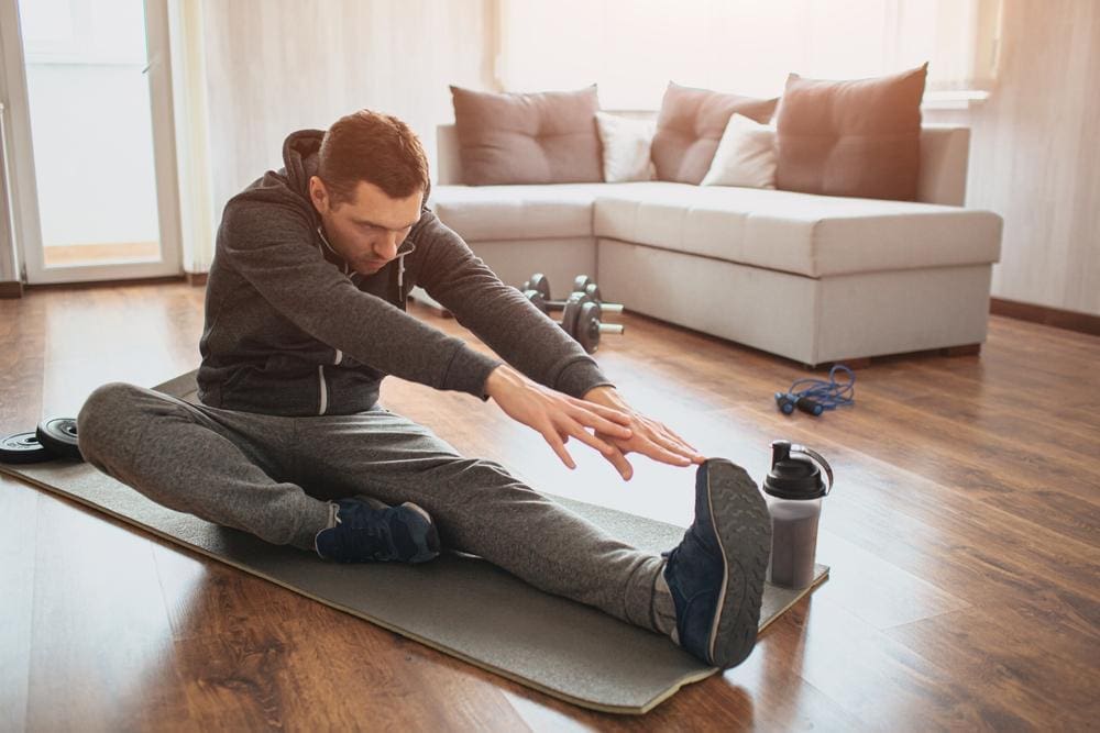 A young man is stretching his legs .