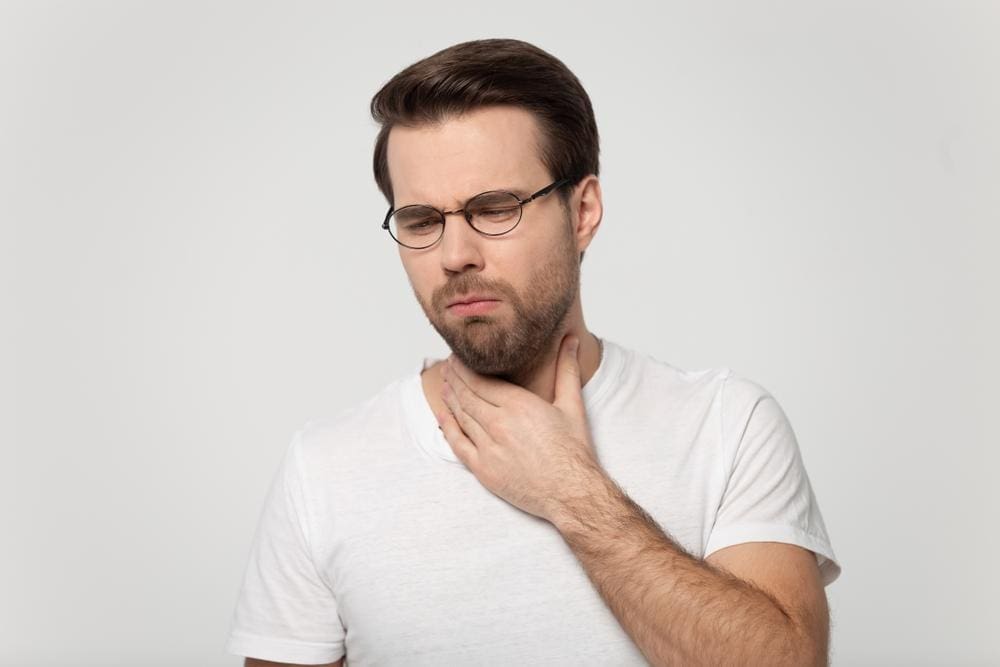 A man is having difficulty swallowing. 