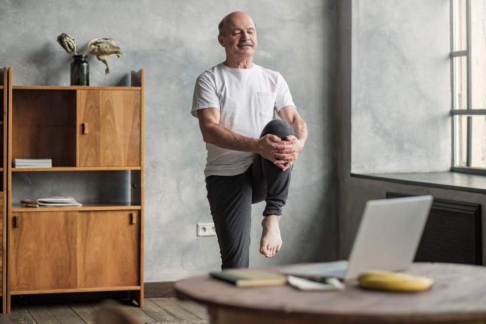 An elderly man is stretching to maintain and improve mobility. 