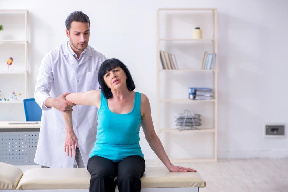 A chiropractor is treating an elderly woman to improve mobility.