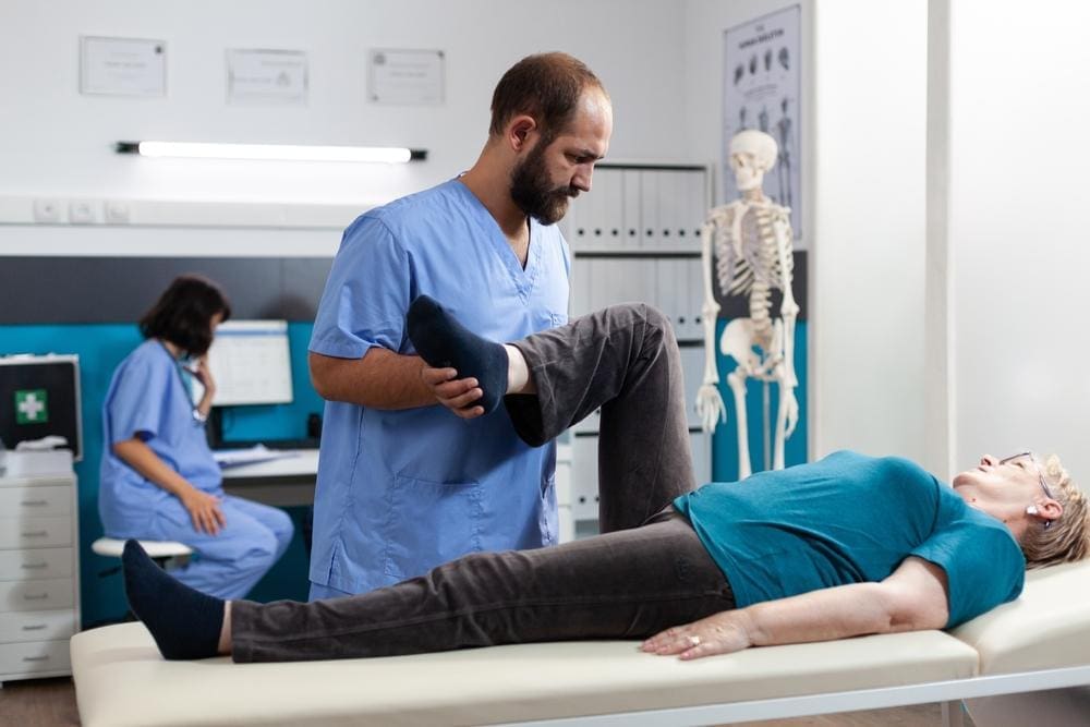 A chiropractor is administering adjustment to alleviate a woman's arthritis pain. 