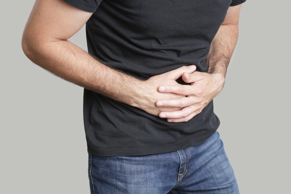 A man is holding his stomach because he is bloated.