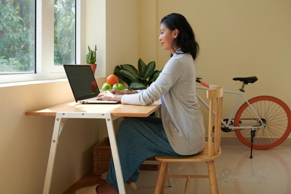 A woman is sitting at her desk, with good posture. 
