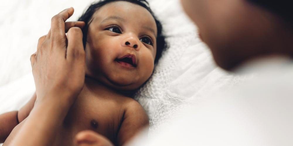 A newborn baby is looking up at his mother.