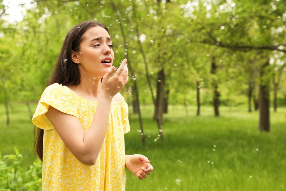 A young woman is outside and suffering from seasonal allergies. 
