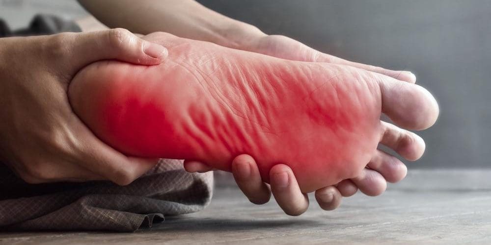 A man is holding his foot because of neuropathy pain.