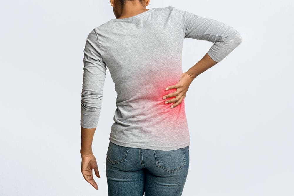 A woman clutching her side suffering pain from kidney stones.
