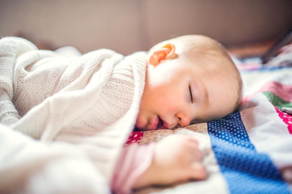 A baby sleeping on her side.