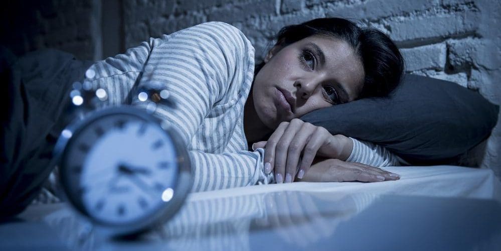 A woman is lying in bed awake, because she cannot sleep.
