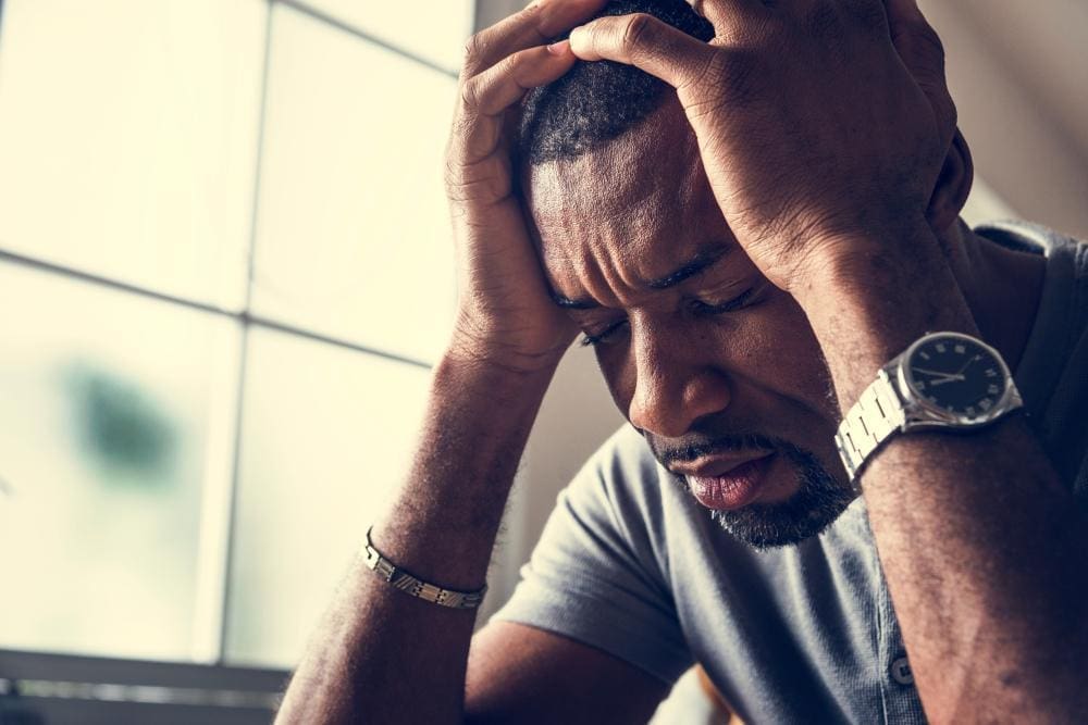 A man is feeling depressed, holding his head in his hands.