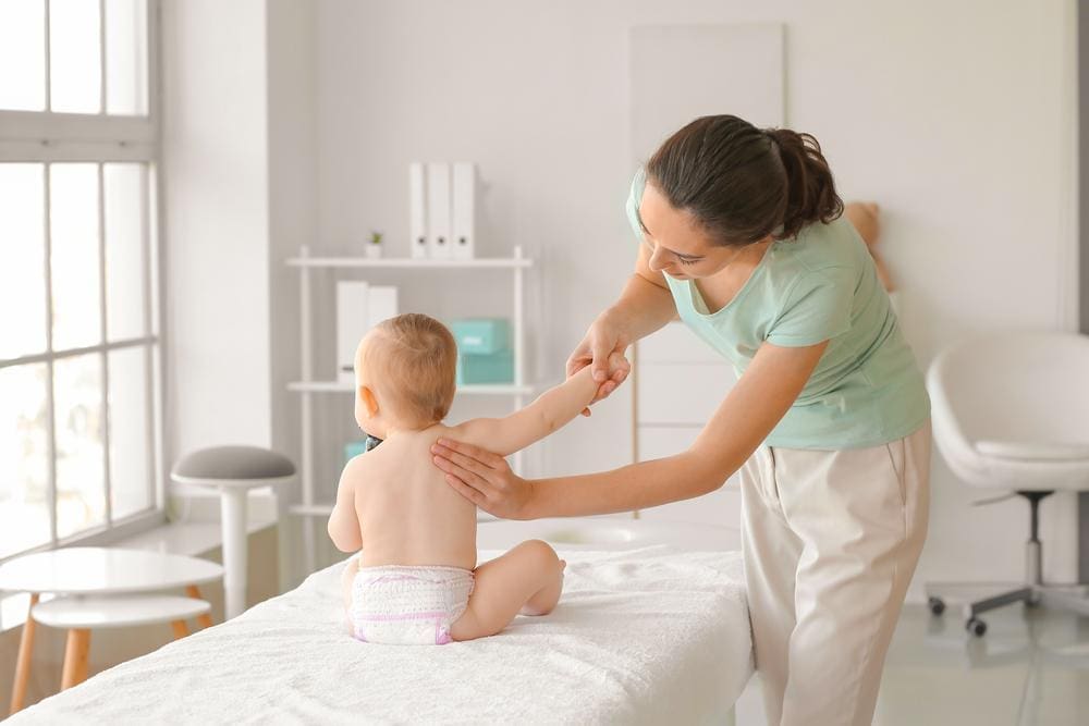 A baby is getting a gentle adjustment from a chiropractor. 