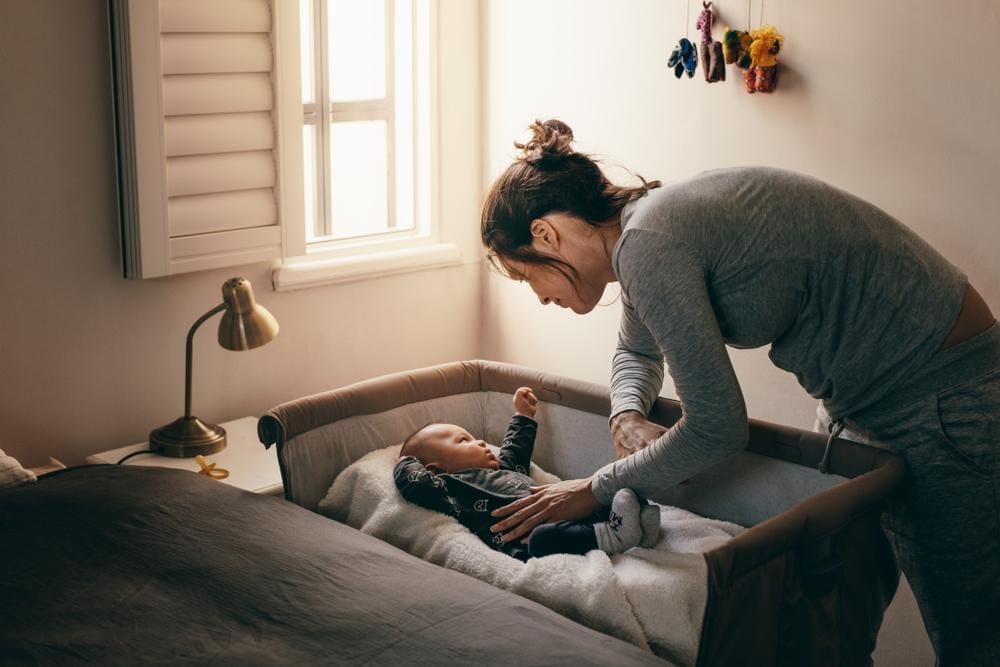 A young mom is trying to put her baby down to sleep for the night.