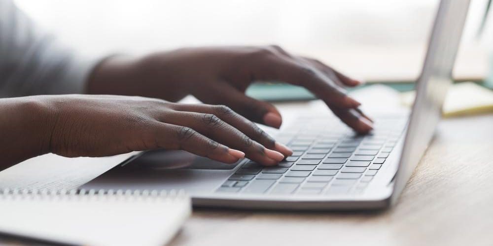 a person's hands typing on a laptop computer.