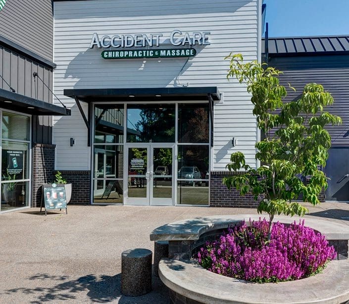 Outside of Forest Grove Chiropractor Clinic showing entrance with flowers and logo sign.