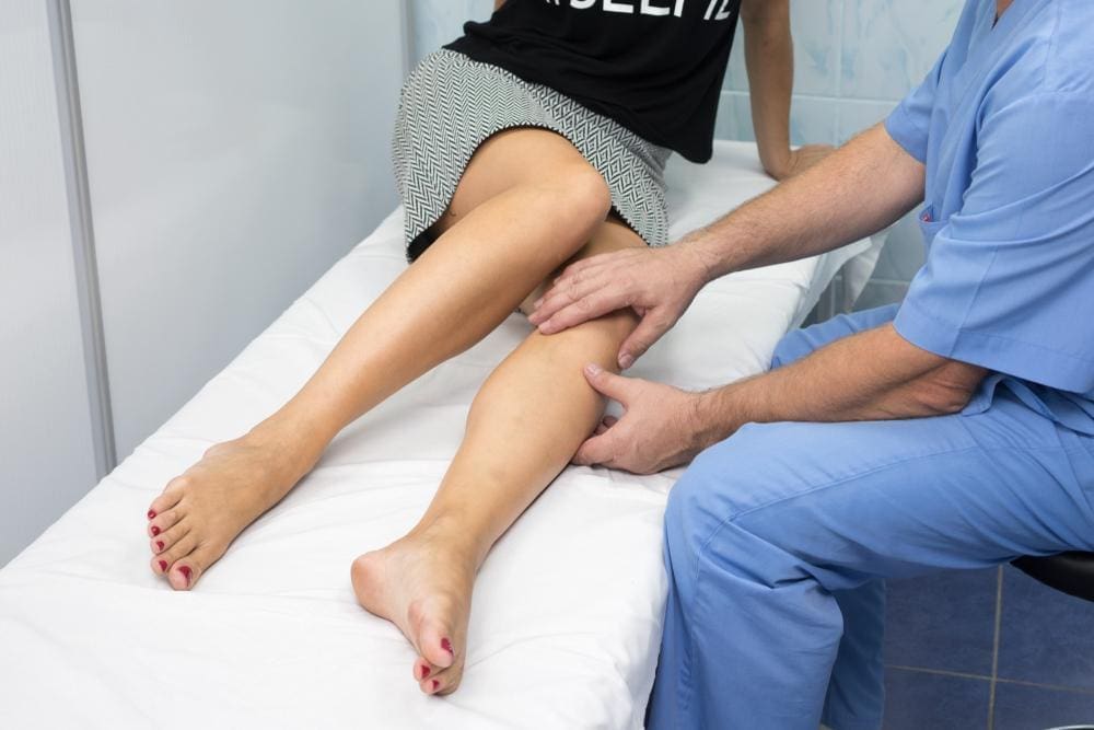 Chiropractor working on knee of female patient.