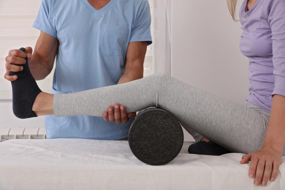 Chiropractor adjusting knee of female patient.
