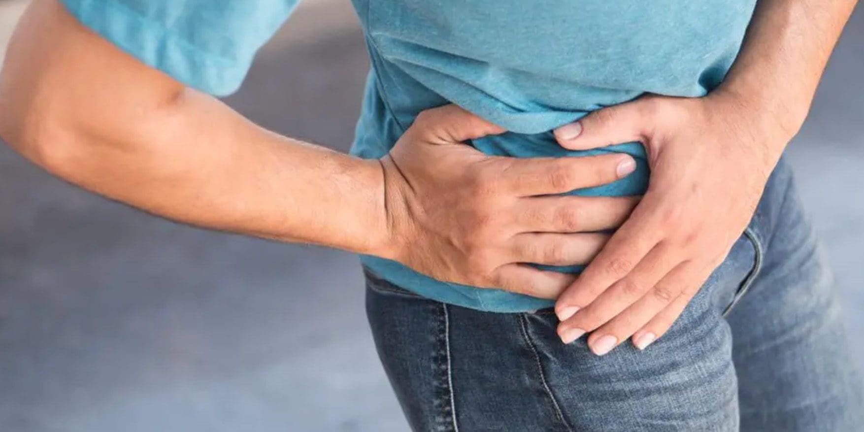 A man is clutching his hip because he suffers from hip bone spurs.