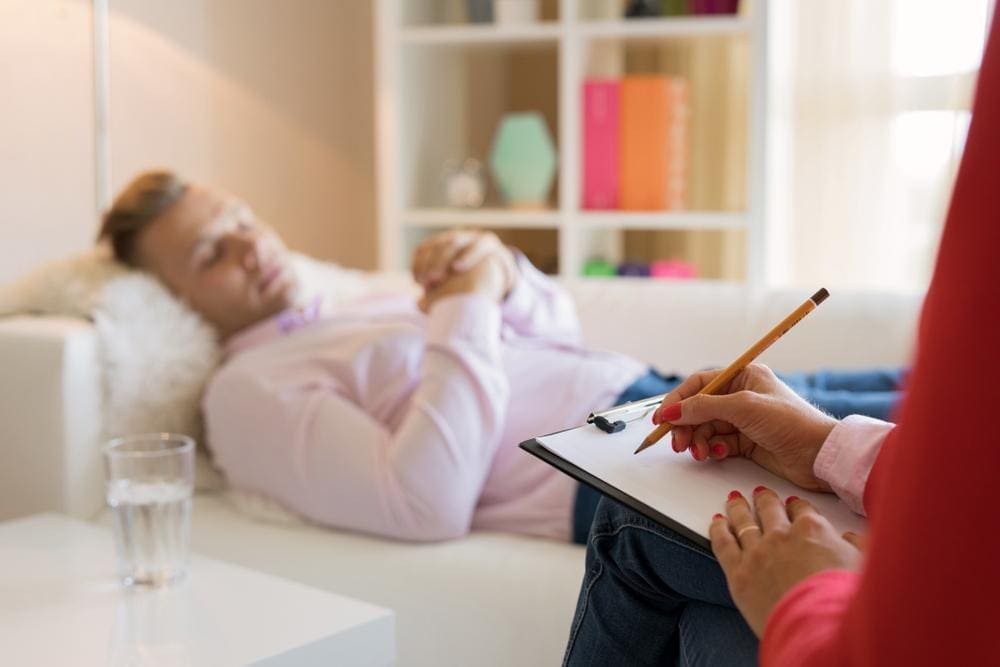 Man lying on couch undergoing hypnotherapy.
