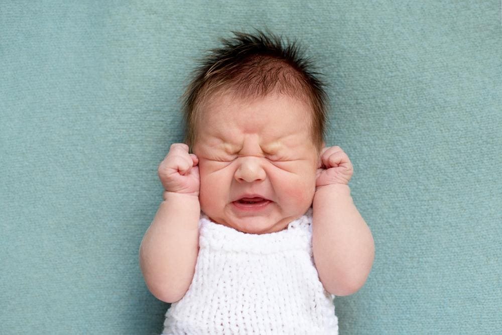 Crying colicky baby with scrunched face.
