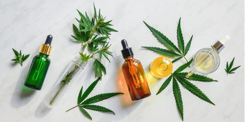 CBD oil in glass bottles with marijuana leaves around them.