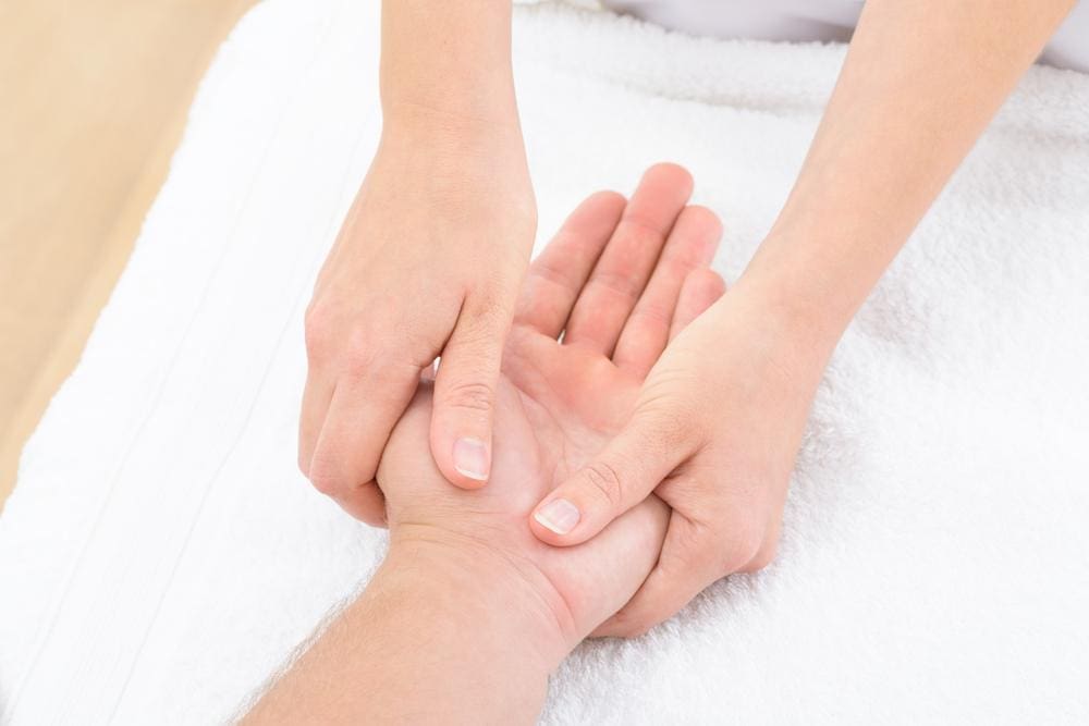 Chiropractor performs palm massage on a patient.