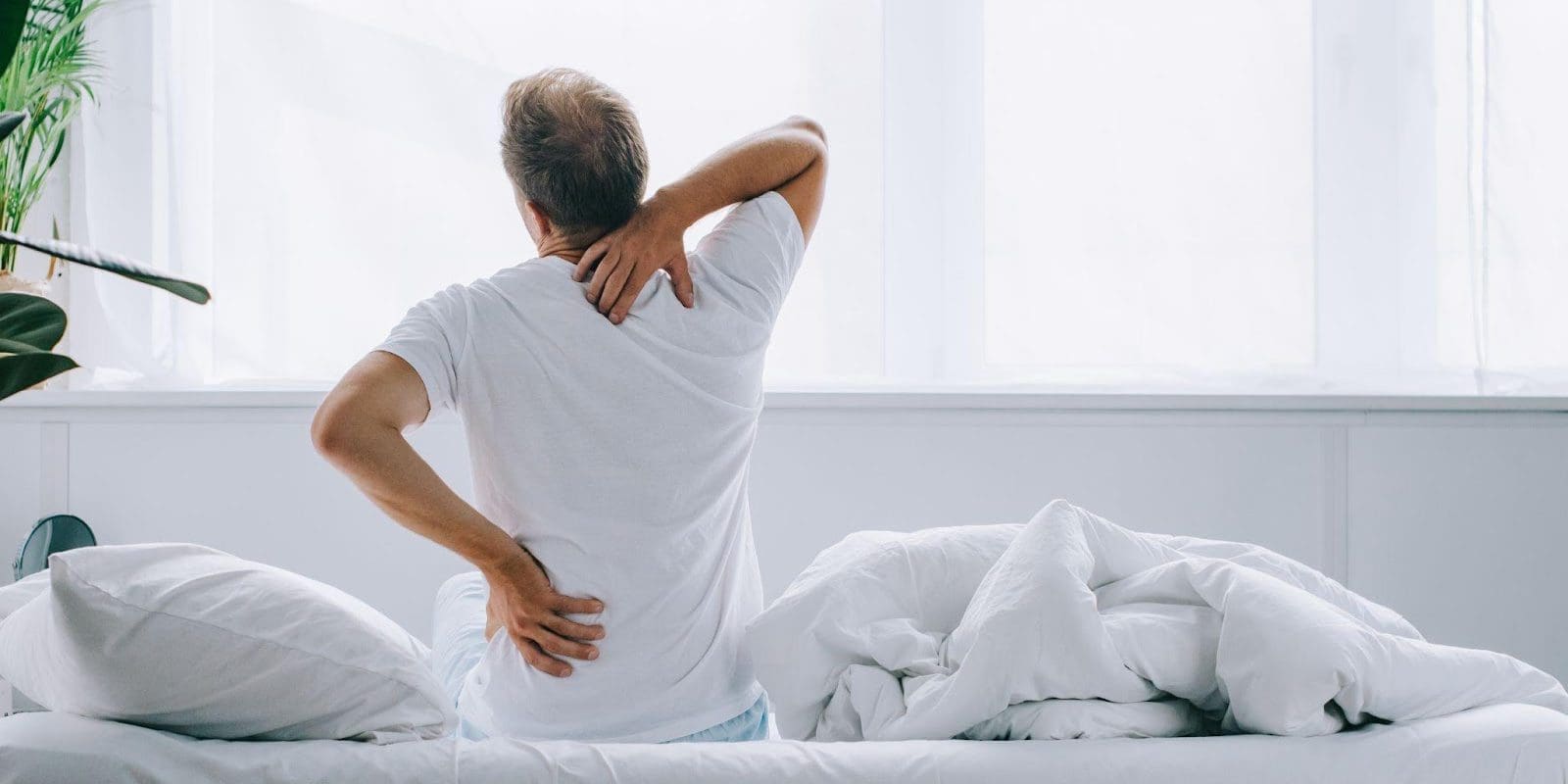 Man with CRPS stretching while sitting on bed.