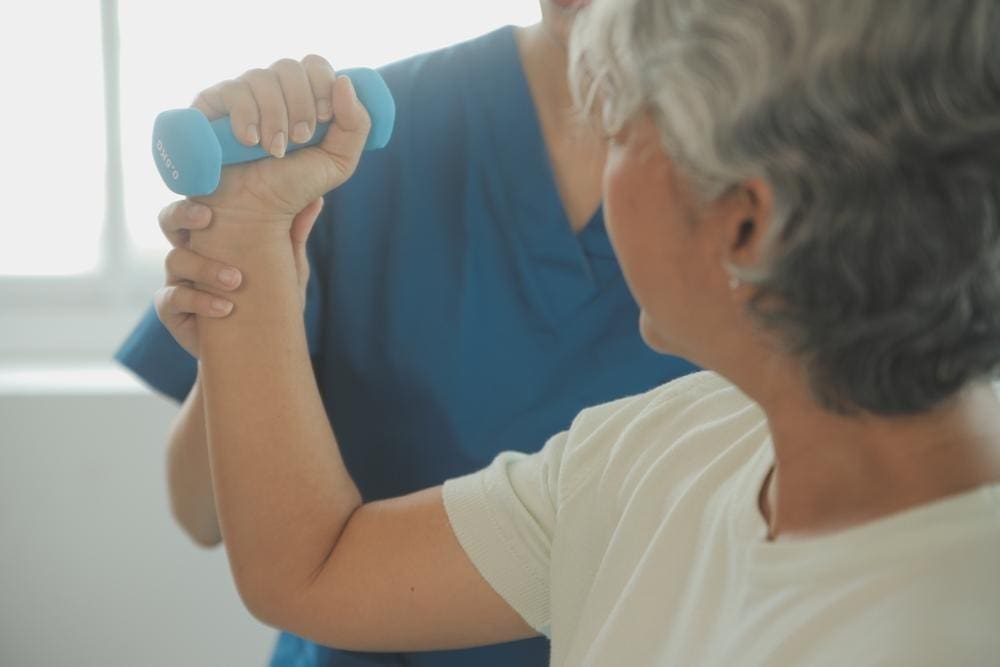 A chiropractor is helping a woman with range of motion physical therapy exercises. 