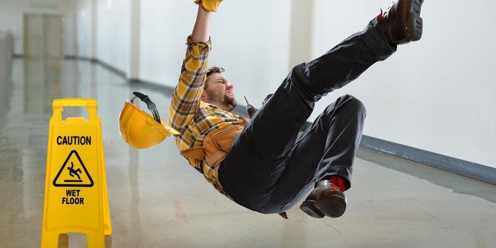 Man has a slip and fall accident next to a wet floor sign.