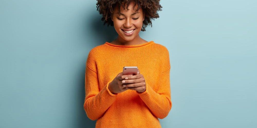 A young woman is looking down at her phone.