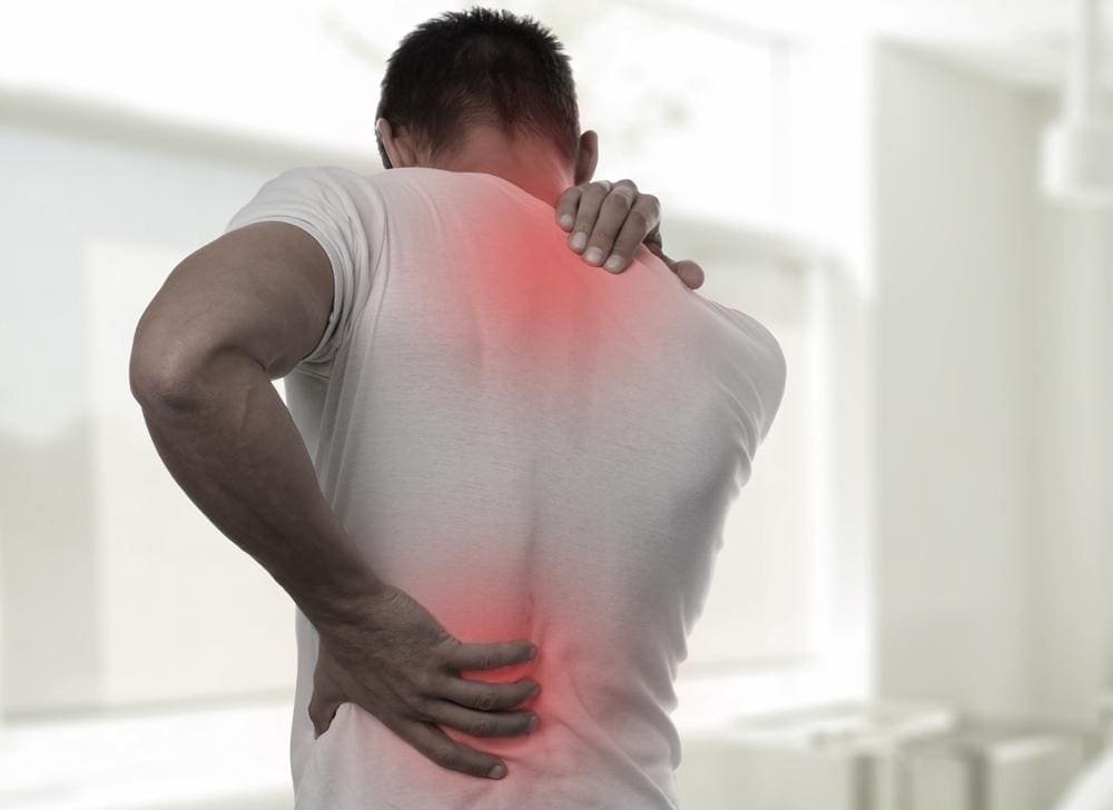 Young man holding his upper and lower back in pain. 

