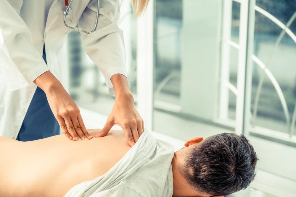 Doctor examining back of male patient.