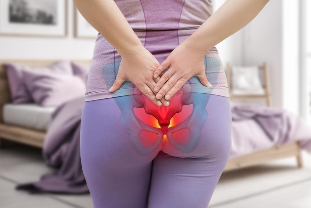 Woman in athletic clothing holding her bruised tailbone.