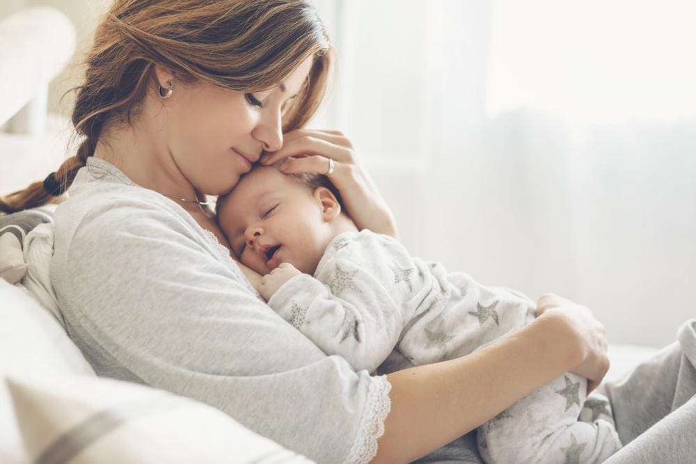 Mother holding her sleeping baby on her chest.
