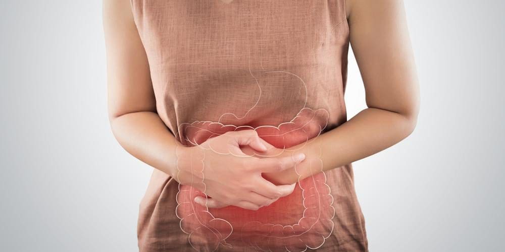 Woman suffering from pudendal neuralgia clutching her inflamed abdomen.