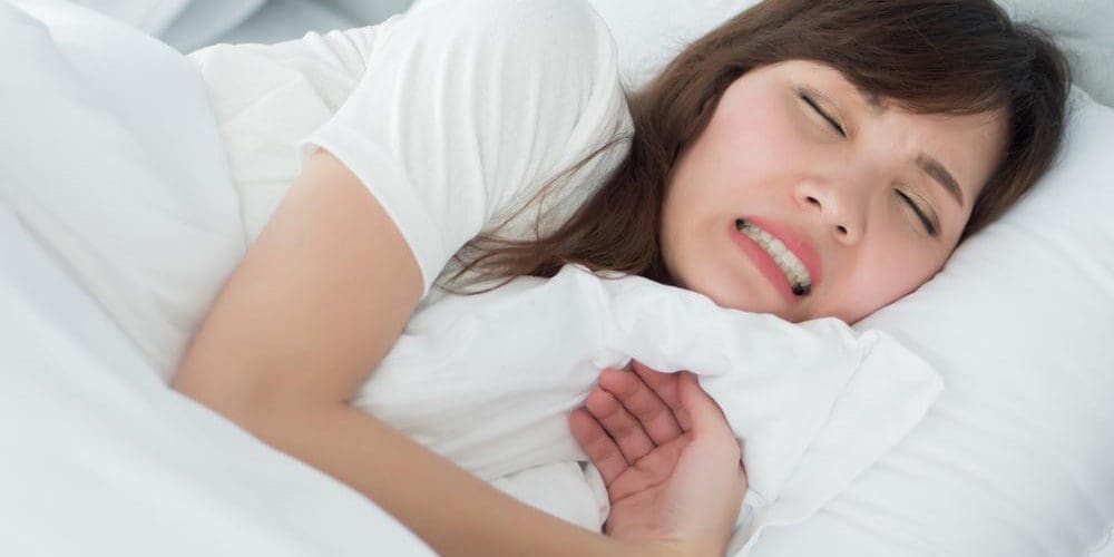 Woman lying in bed grinding her teeth.
