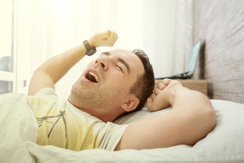 Young man stretching after waking up from a restful sleep.