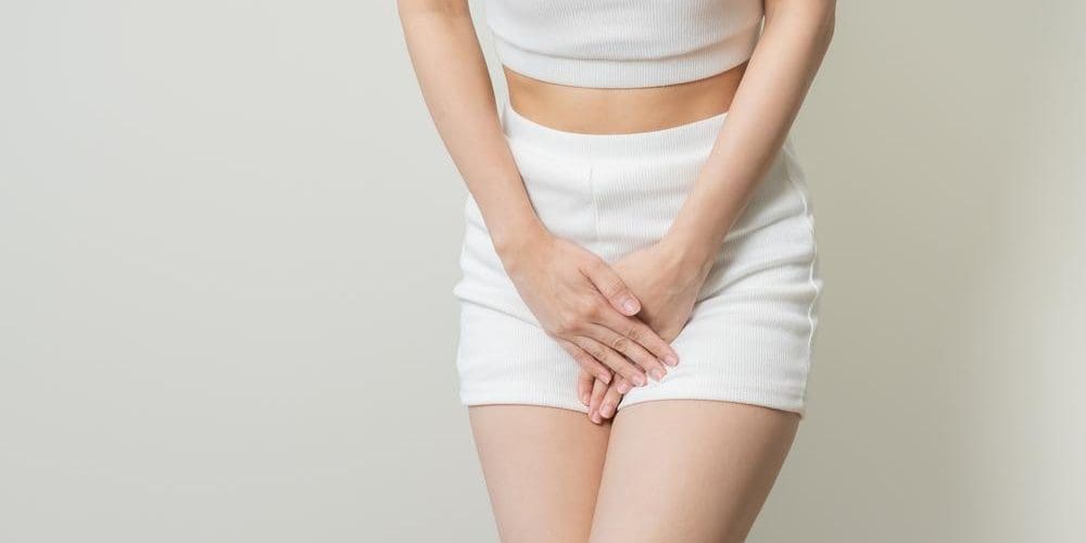 Woman standing with her legs crossed and hands over her bladder.