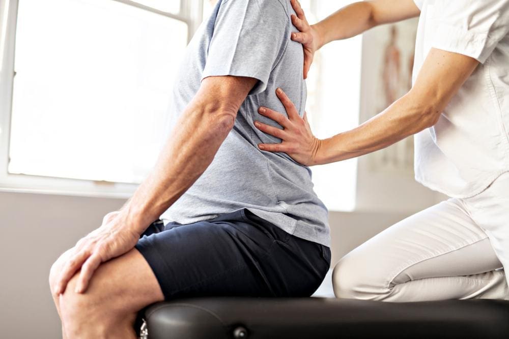 Chiropractor adjusts the lower spine of a male patient.

