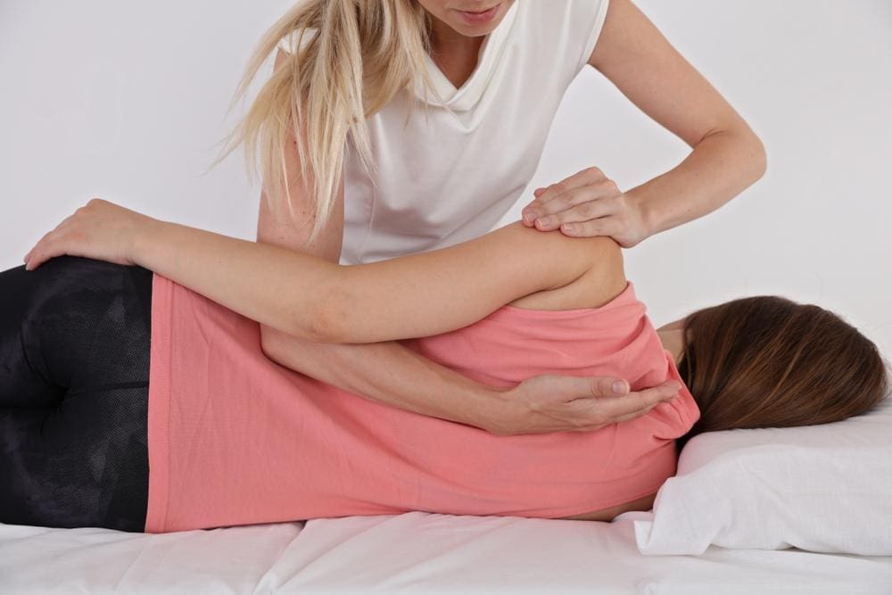 Chiropractor adjusts a woman's spine.