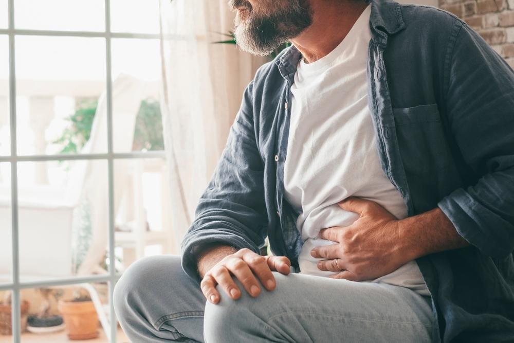 Middle-aged man in pain from gastroparesis with his hand on his stomach.