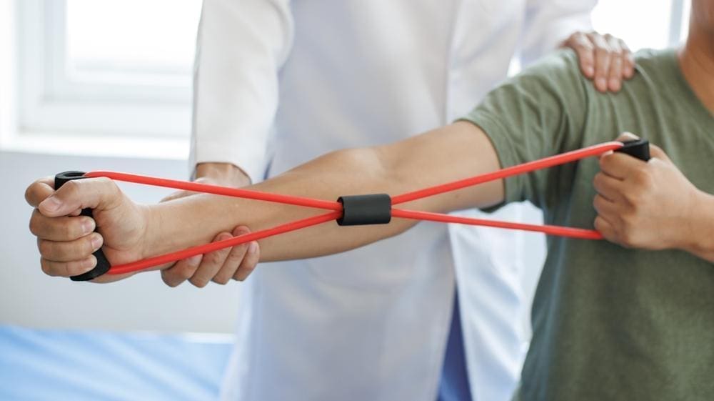Man with Parkinson's disease does upper body strength exercises with chiropractor.