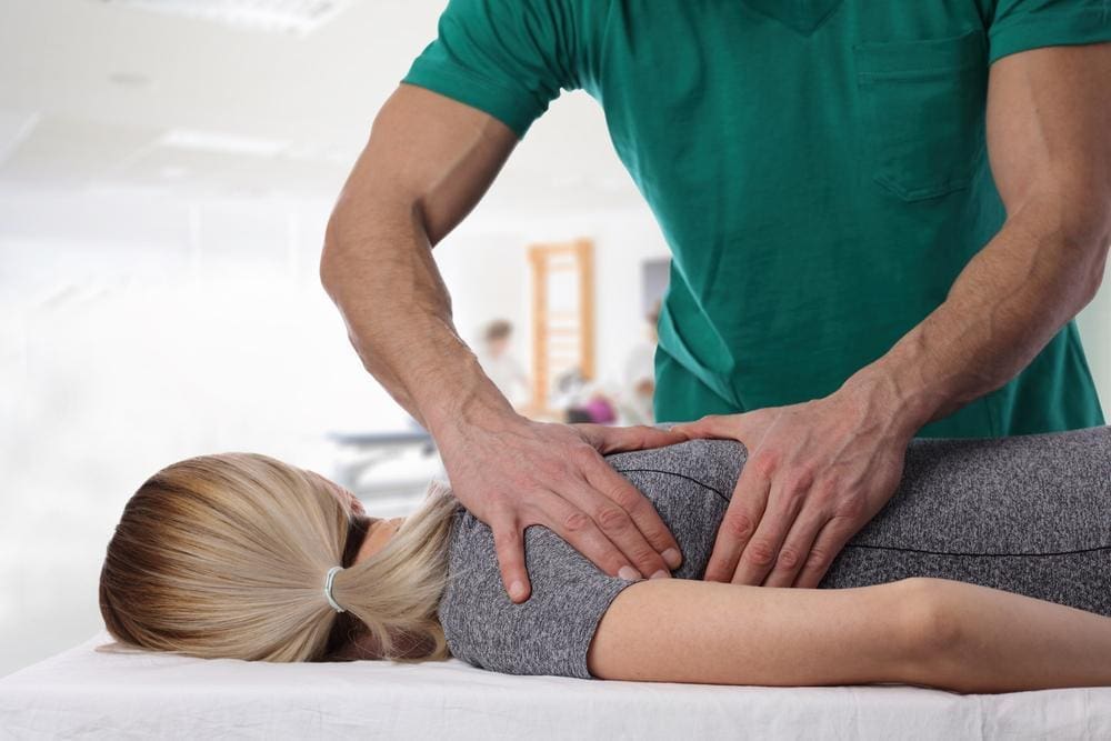 Chiropractor adjusting a young woman's back.