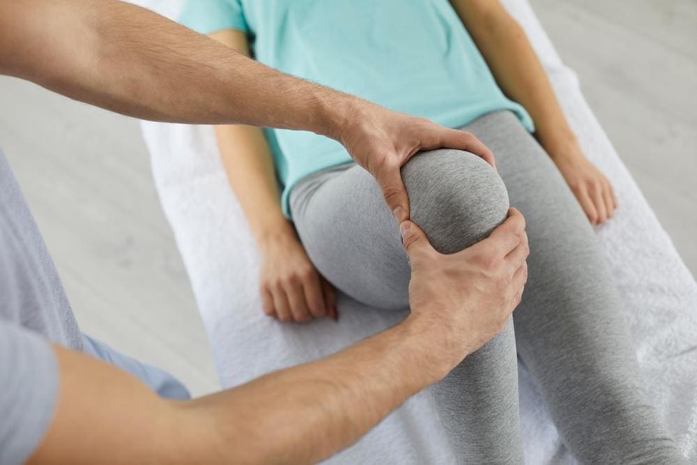 Chiropractor adjusting a patient's knee.